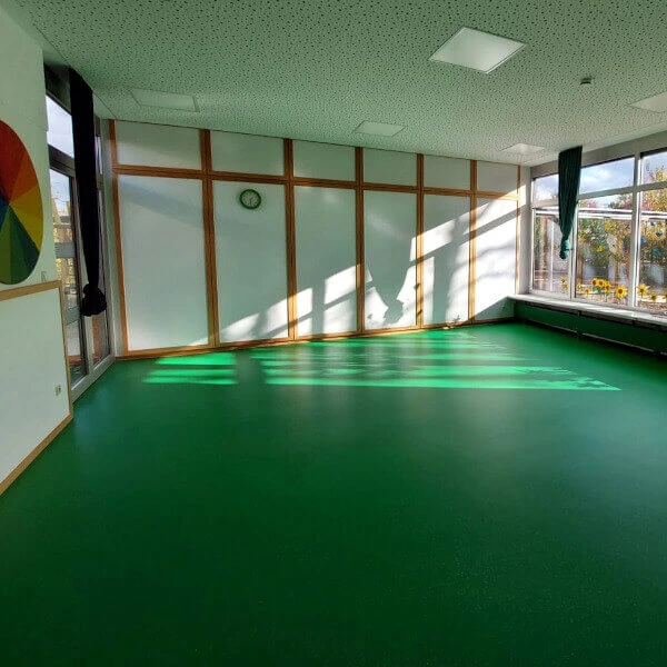 Ein grüner Boden in einem Innenraum, der vermutlich zu einer Schule oder einem Kindergarten gehört